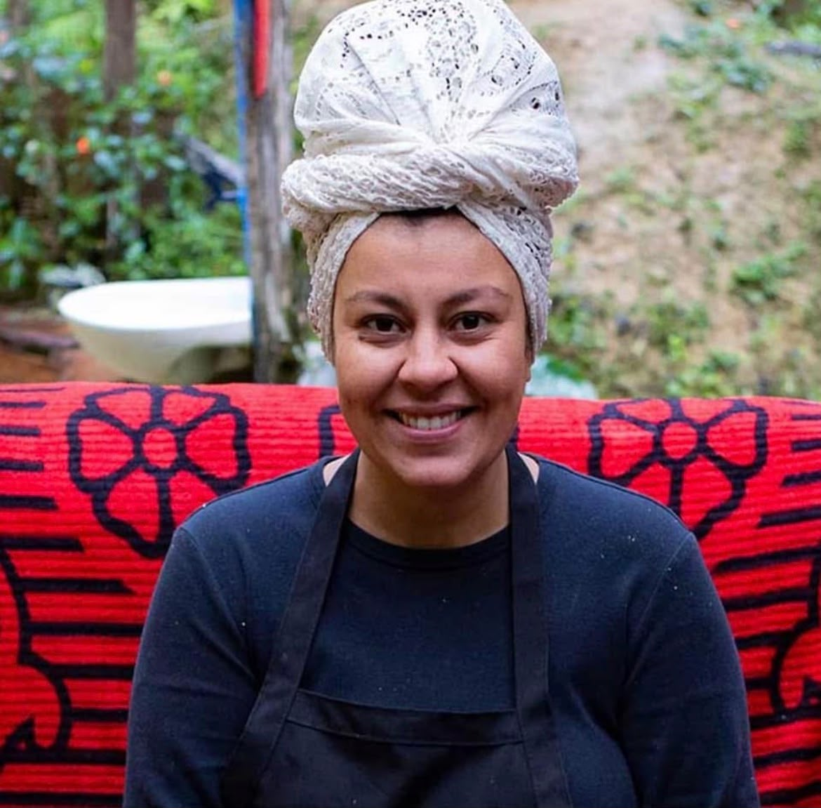 Chef Aline Rocha sorrindo, de turbante branco e avental